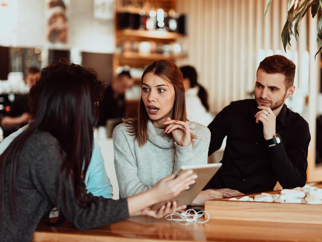 A group of friends hanging out in a cafe, and among them is a tablet. photo