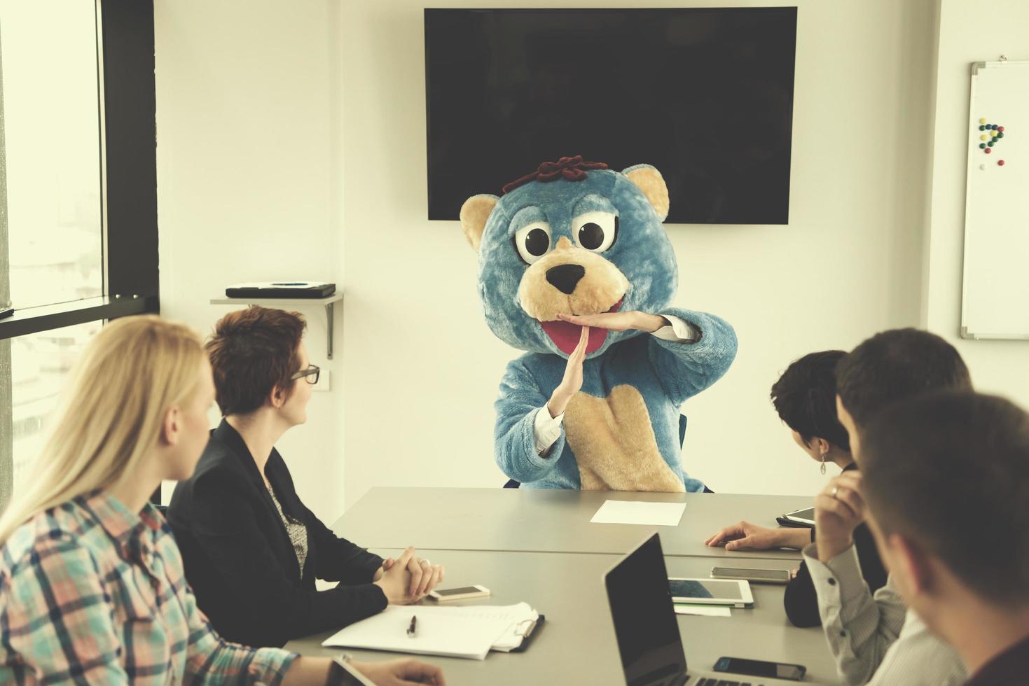 boss dresed as bear having fun with business people in trendy office photo