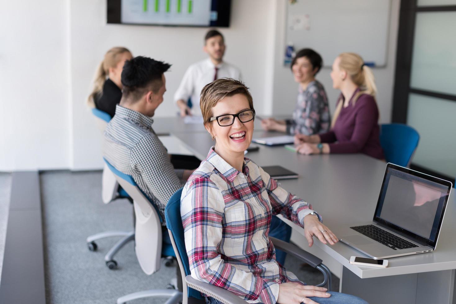 portrait of young business woman at office with team on meeting in background photo