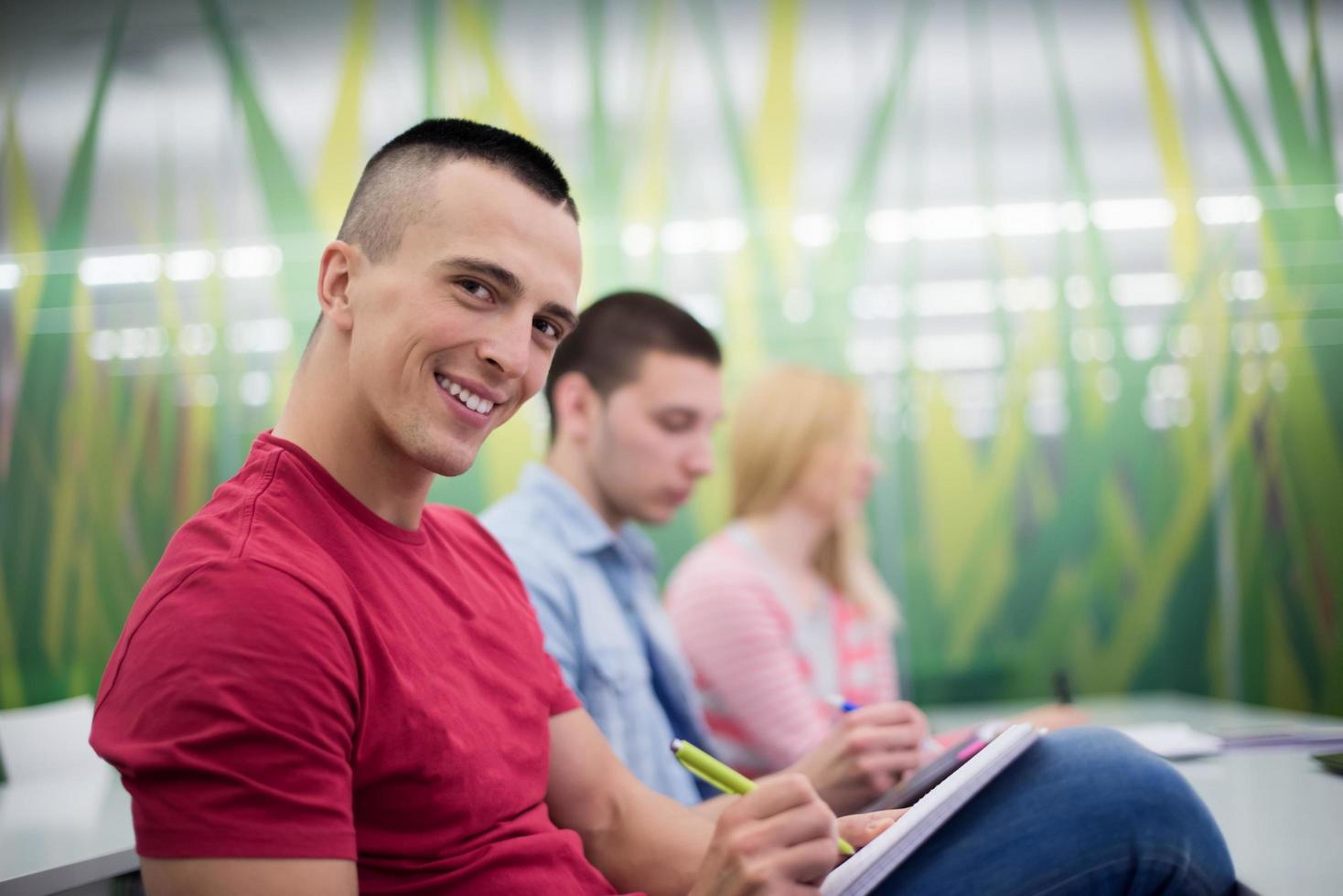 male student taking notes in classroom photo