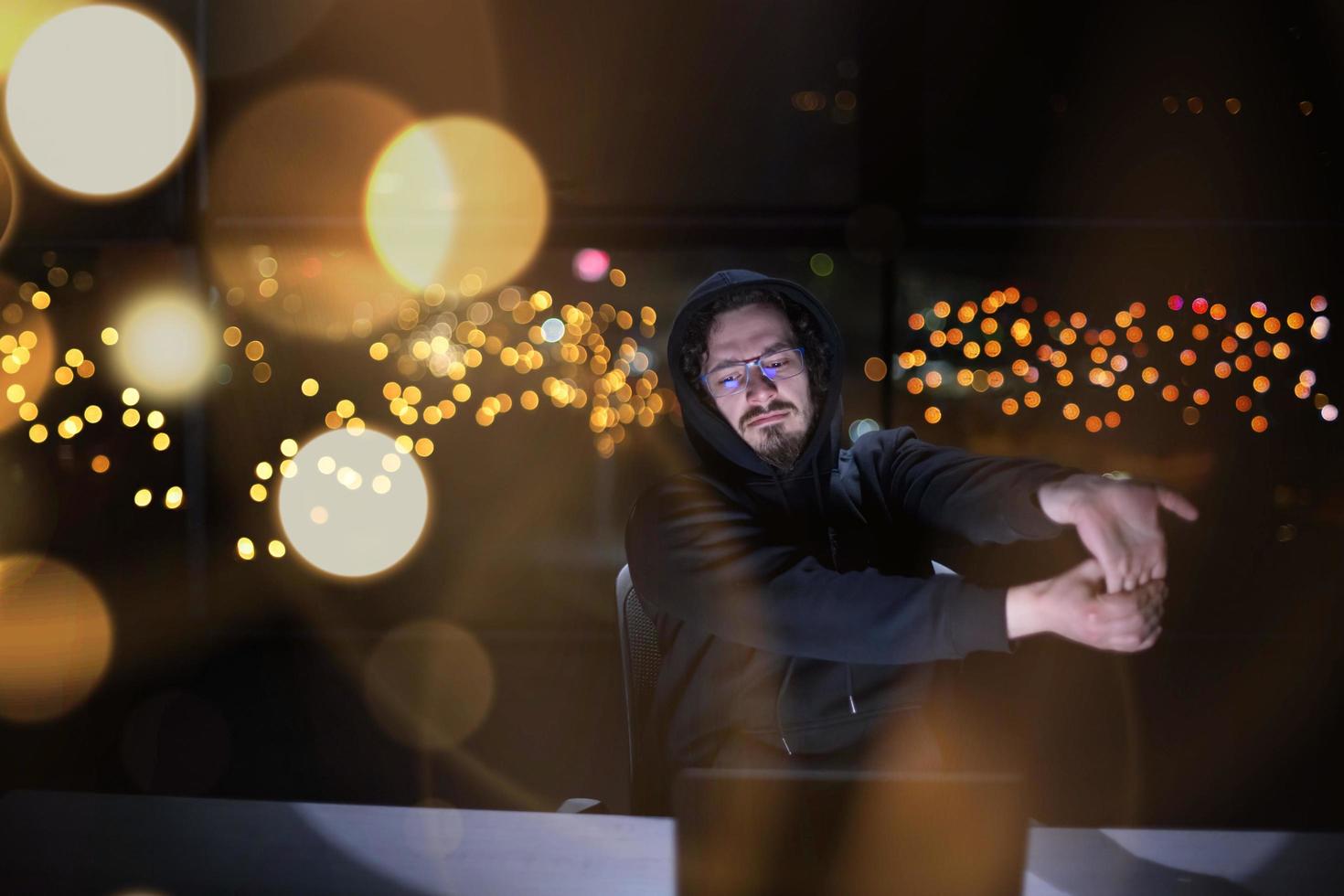 hacker using laptop computer while working in dark office photo