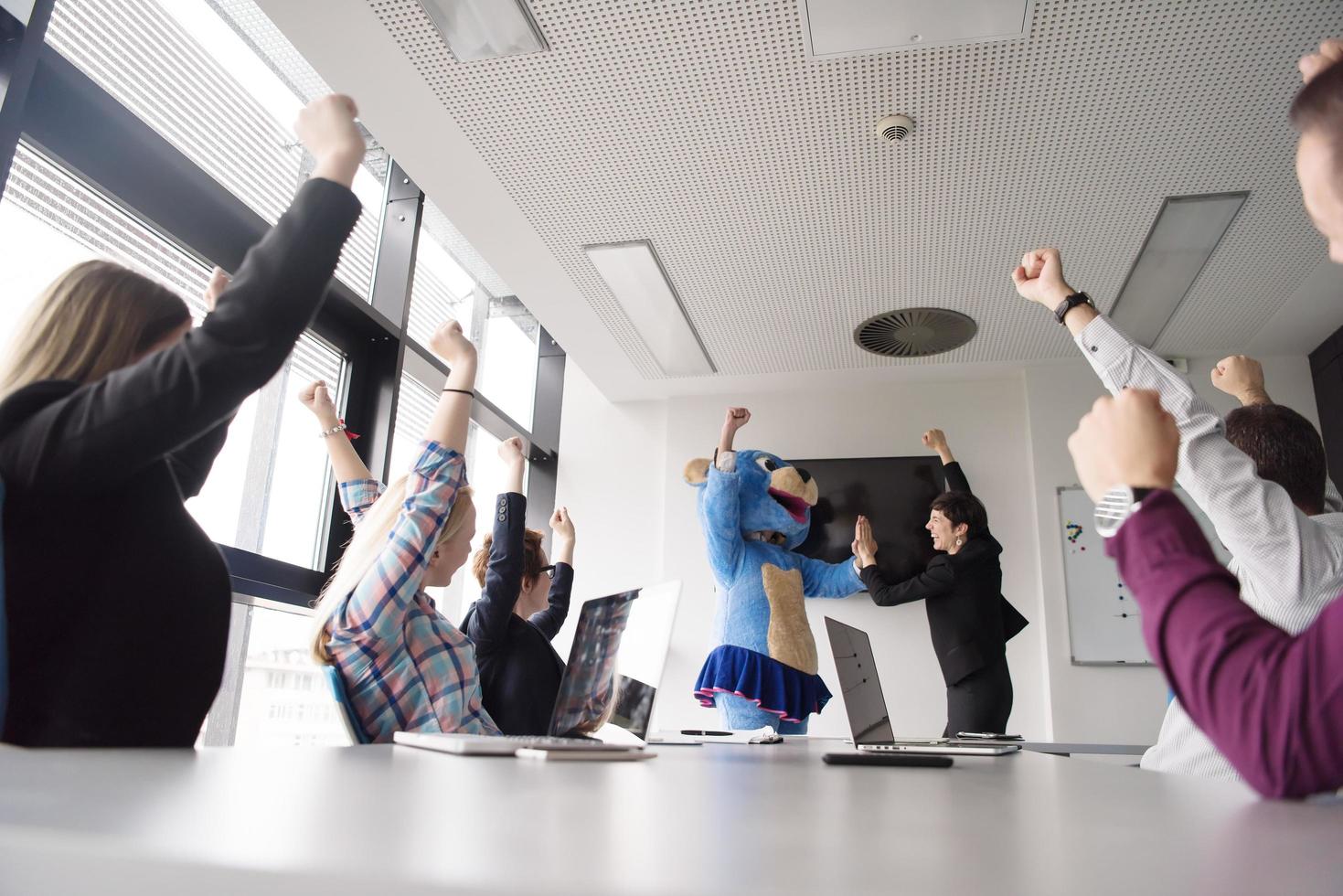 boss dresed as bear having fun with business people in trendy office photo