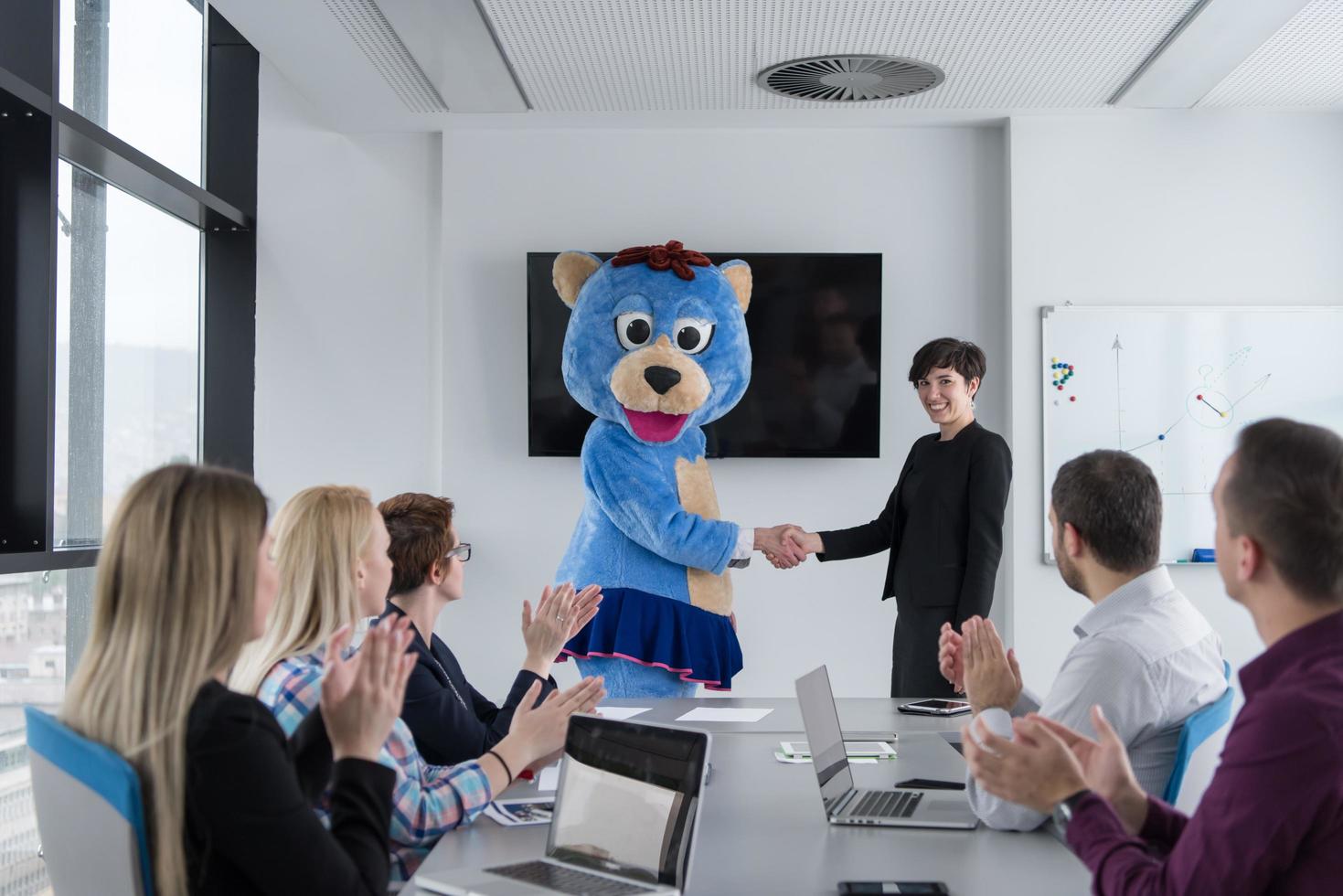 boss dresed as bear having fun with business people in trendy office photo