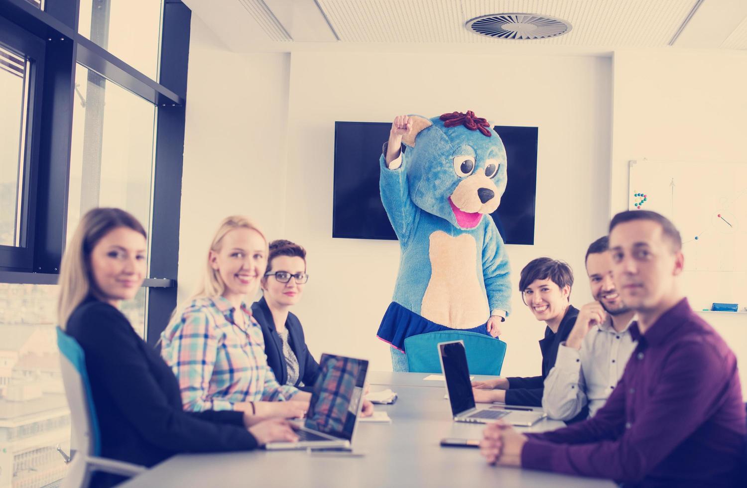 boss dresed as bear having fun with business people in trendy office photo