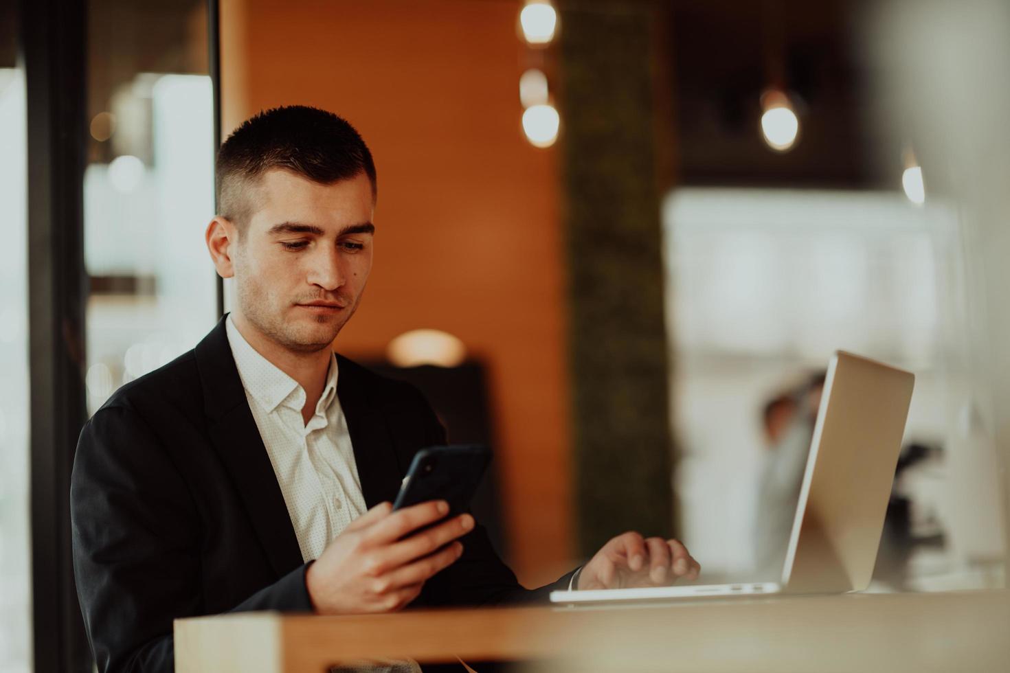 feliz hombre de negocios sentado en la cafetería con laptop y smartphone. foto