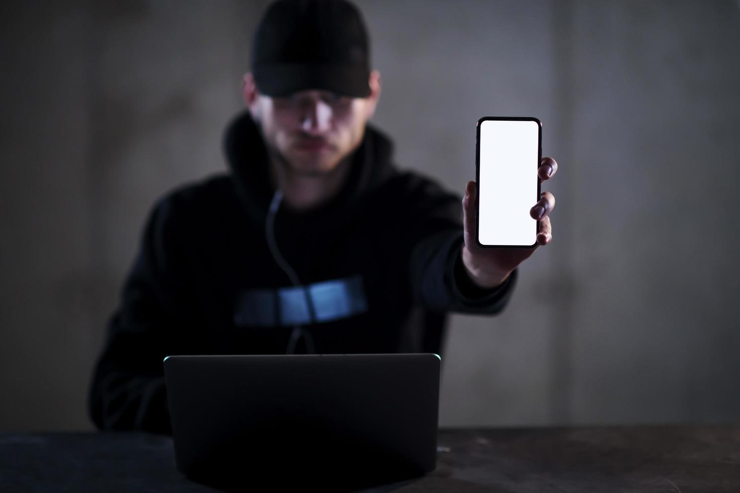 criminal hacker using laptop computer while working in dark office photo