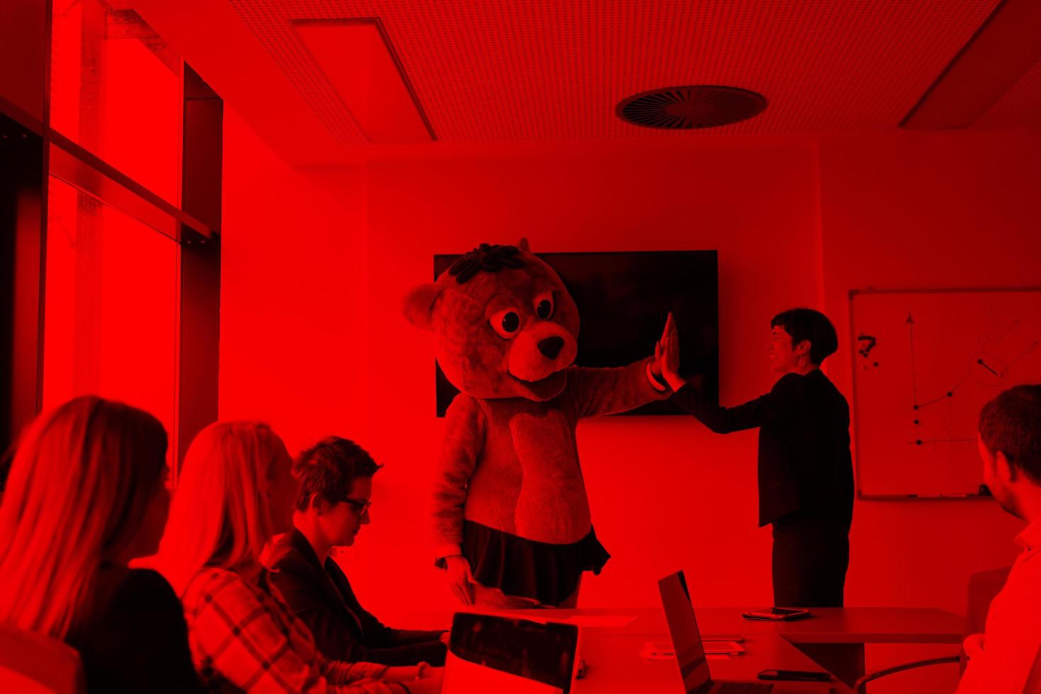 boss dresed as bear having fun with business people in trendy office photo