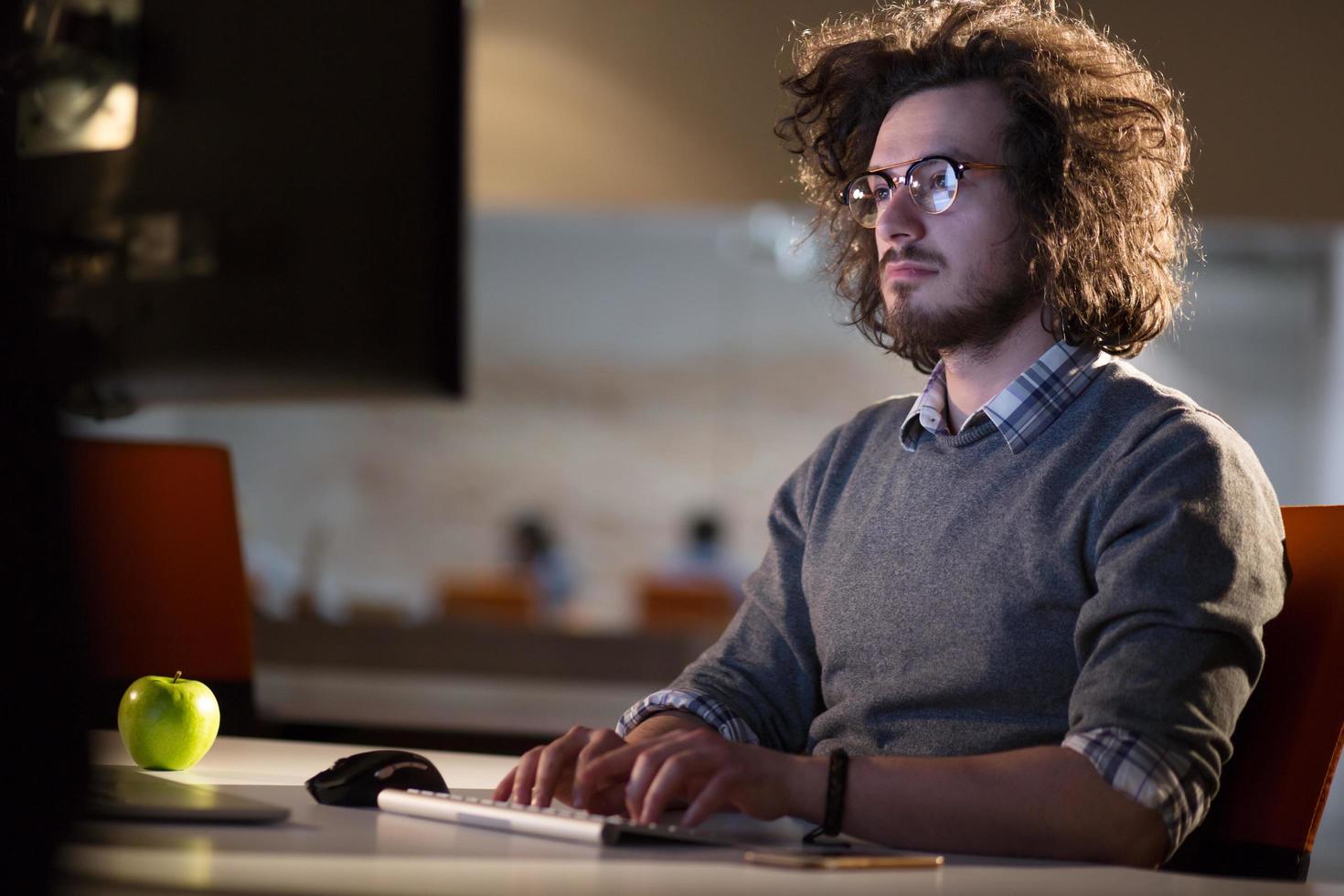 man working on computer in dark office photo