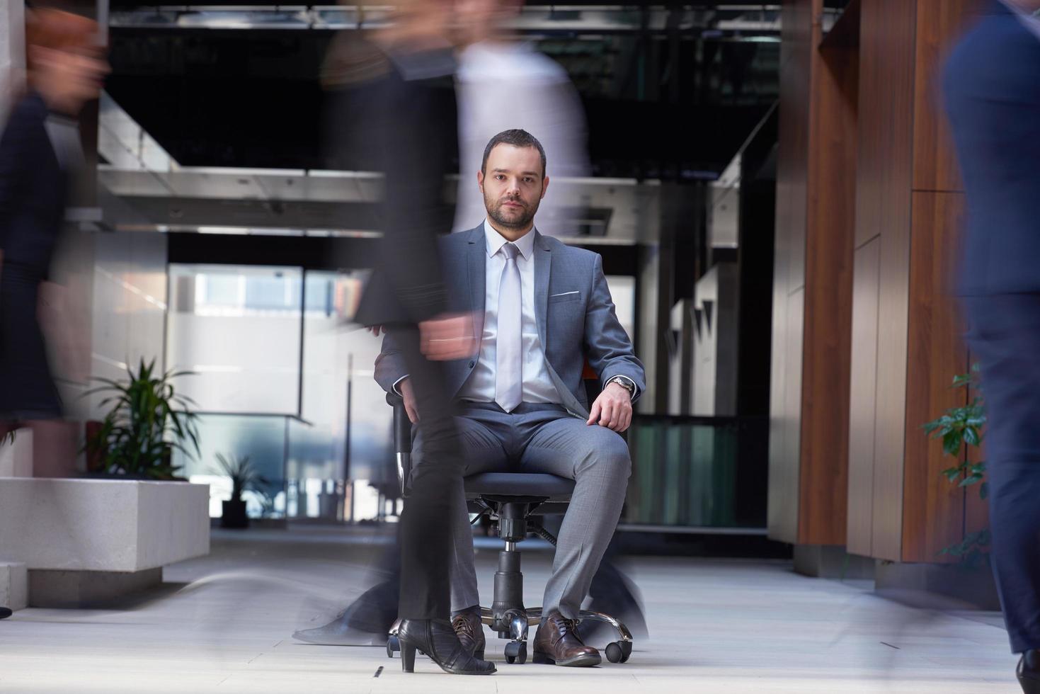 business man sitting in office chair, people group  passing by photo