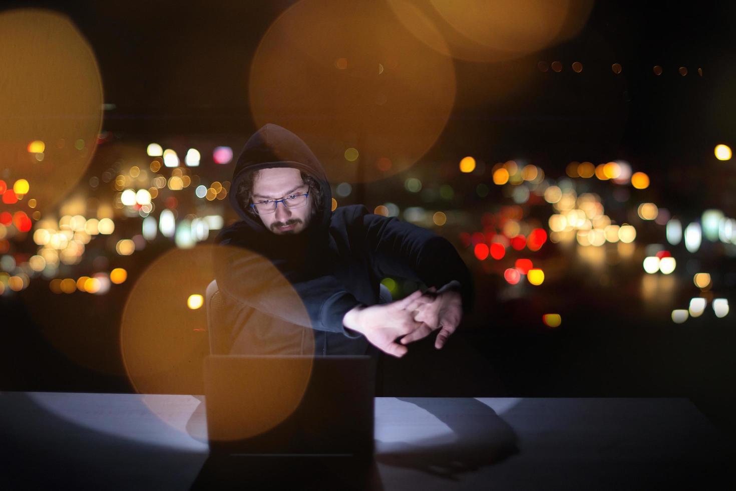 hacker using laptop computer while working in dark office photo