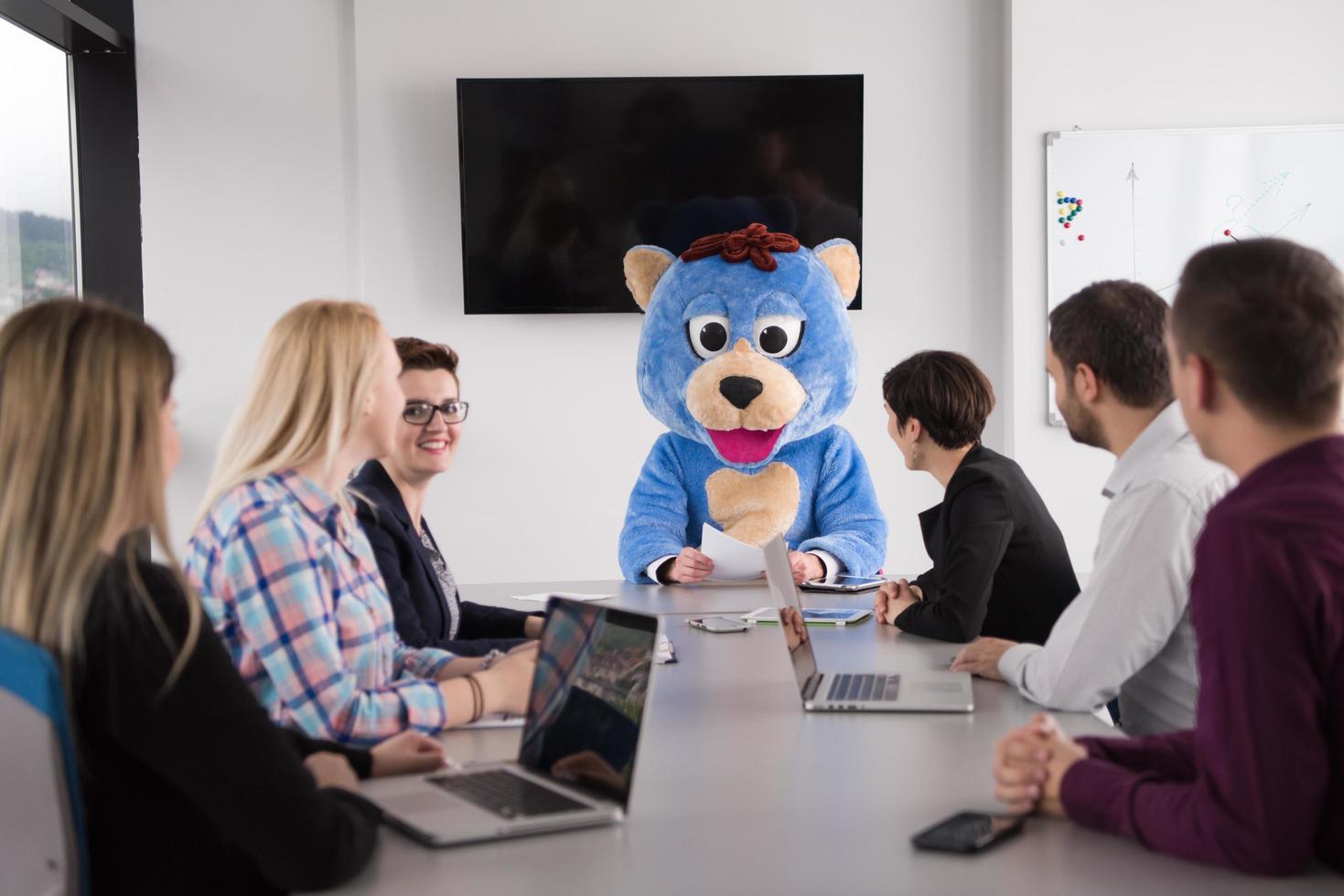 boss dresed as bear having fun with business people in trendy office photo
