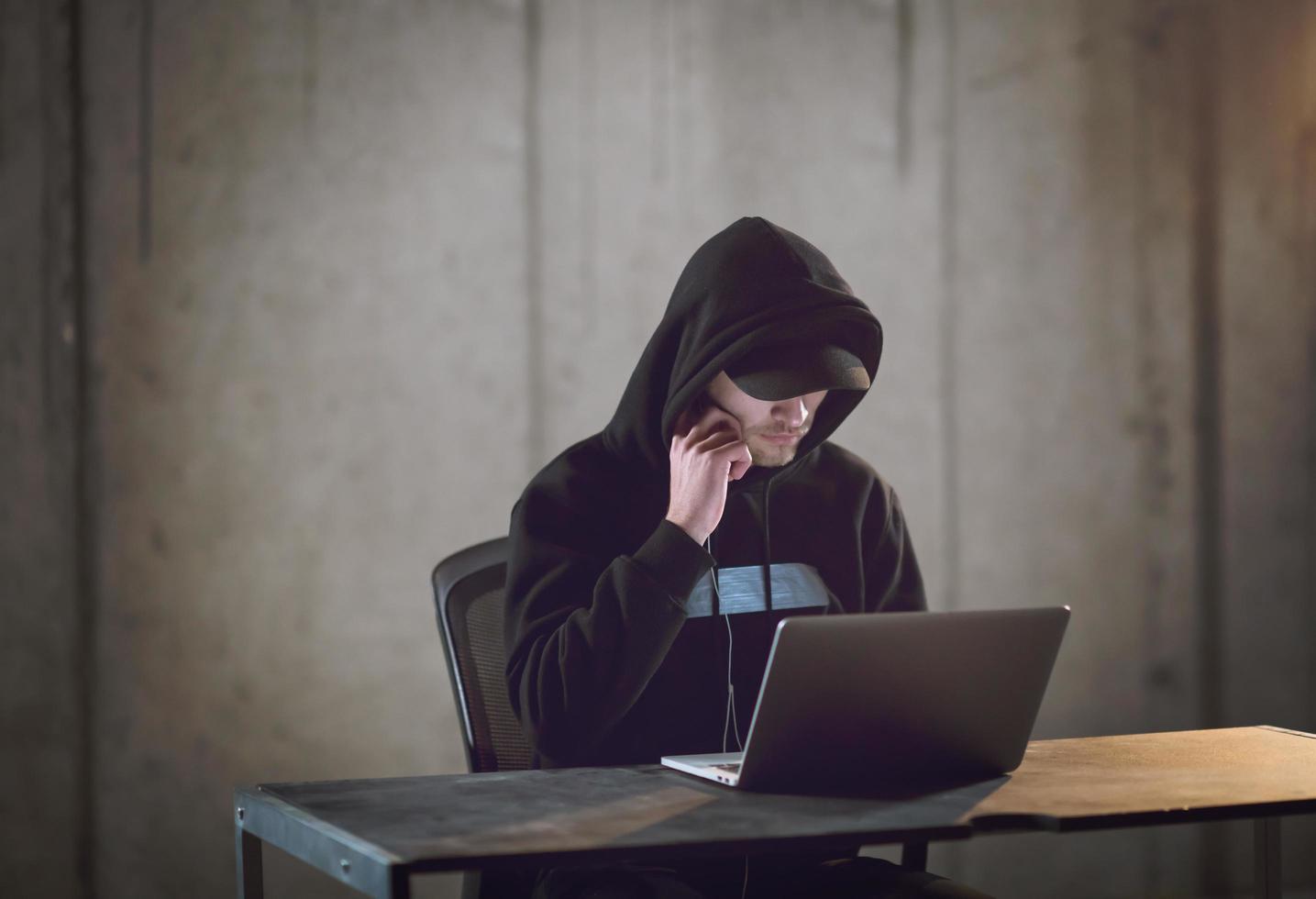 talented hacker using laptop computer while working in dark office photo