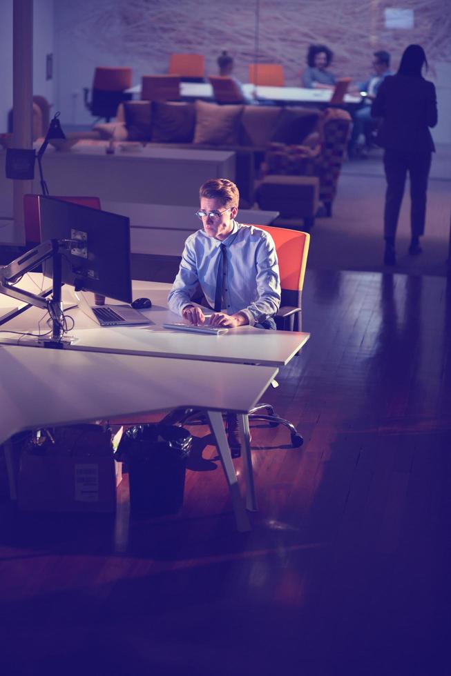hombre trabajando en una computadora en una oficina oscura foto