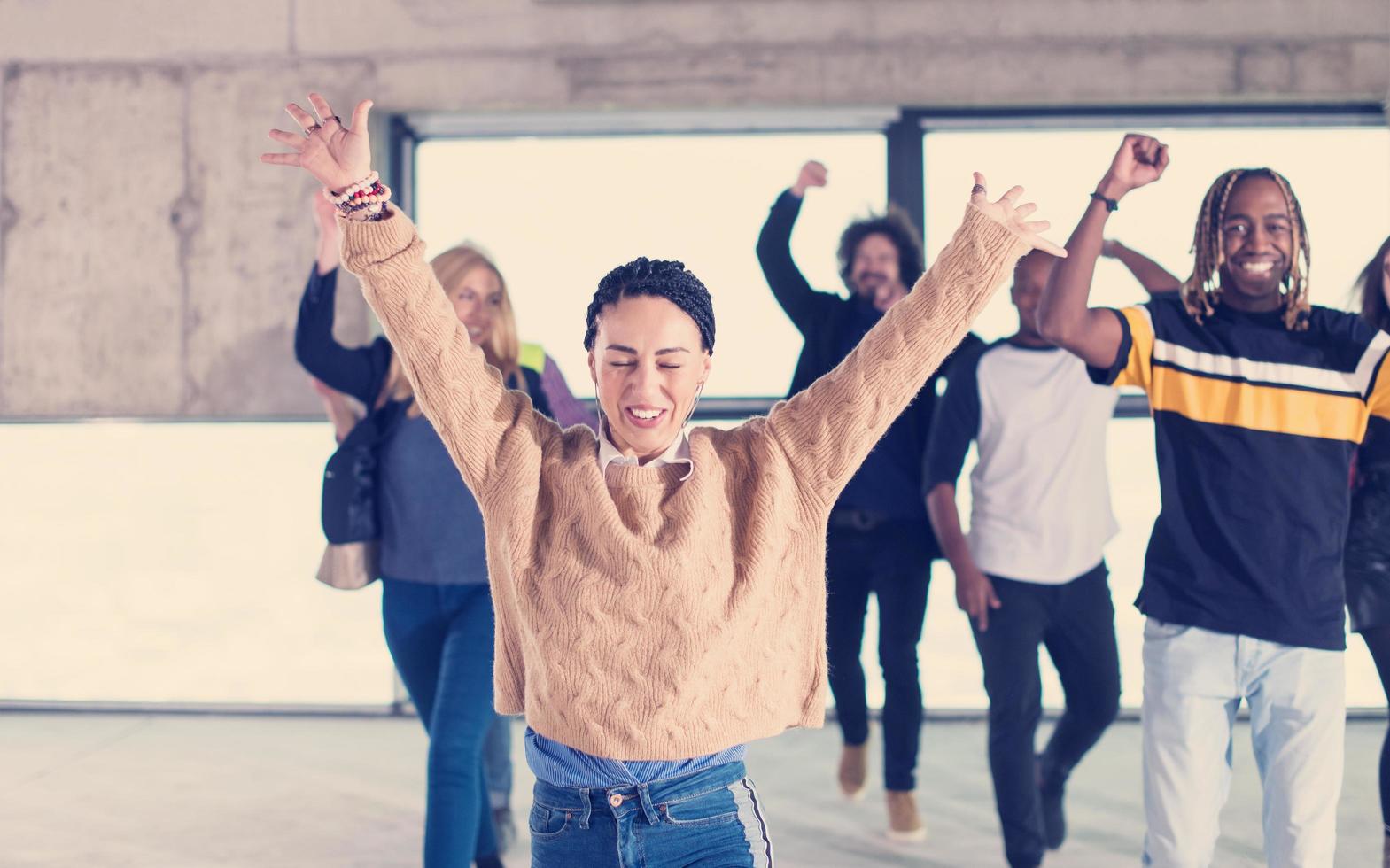 jóvenes empresarios multiétnicos bailando en una oficina de inicio sin terminar foto