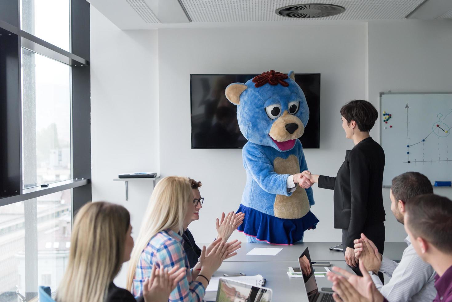 boss dresed as bear having fun with business people in trendy office photo