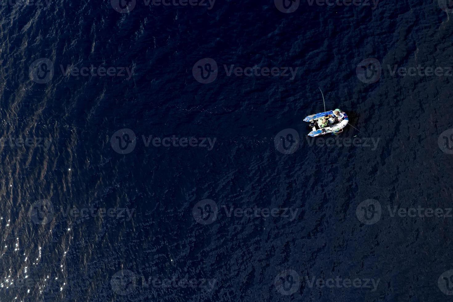 inflatable boat with fishermen in the middle of the lake top view photo