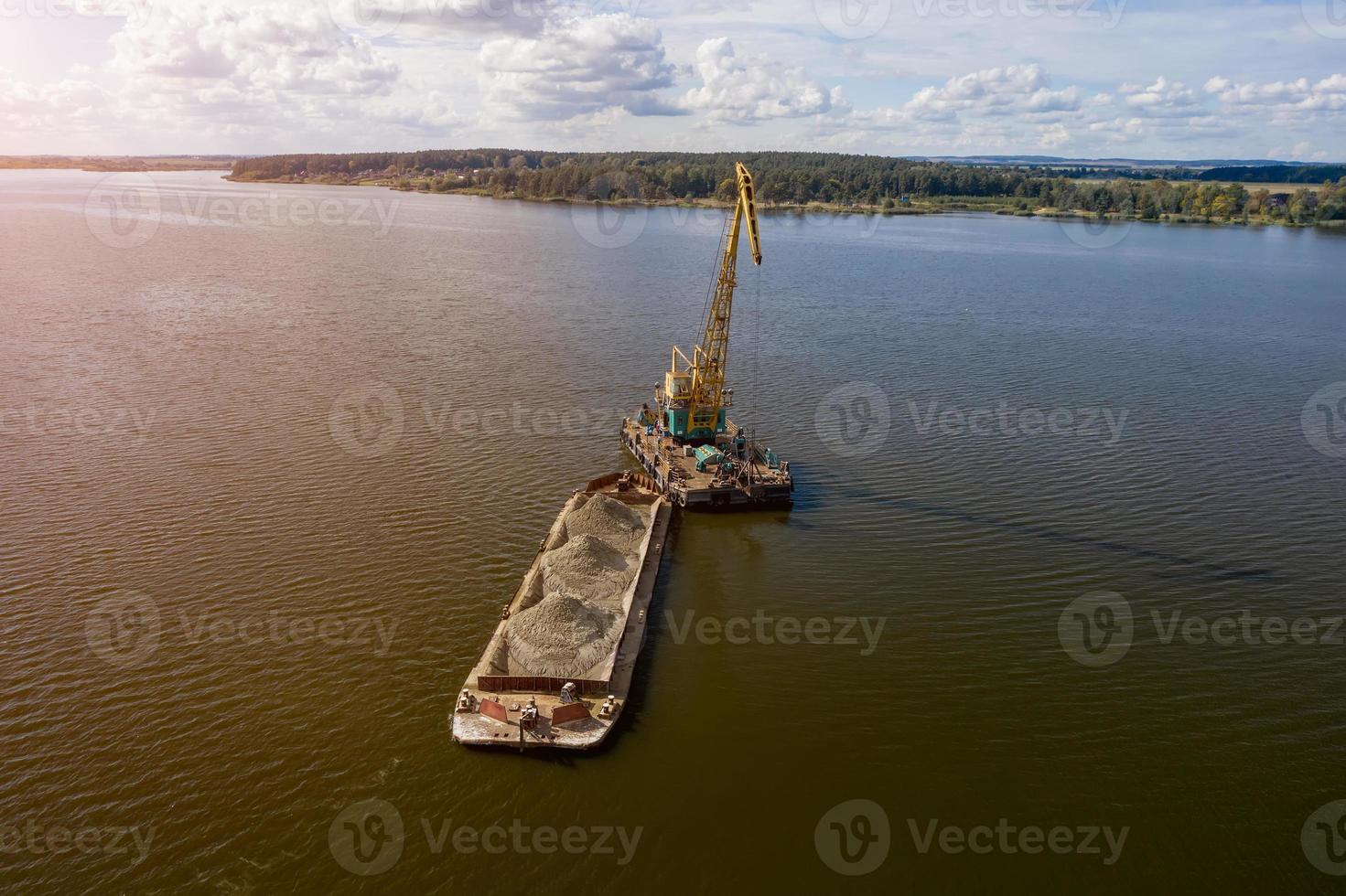 Cleaning the river bottom with a crane and a barge top view photo