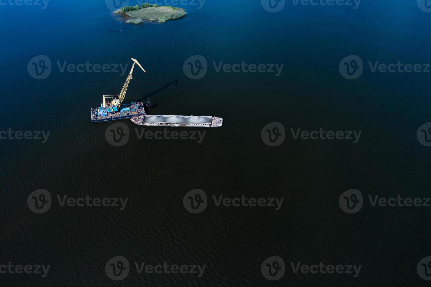Cleaning the river bottom with a crane and a barge top view photo
