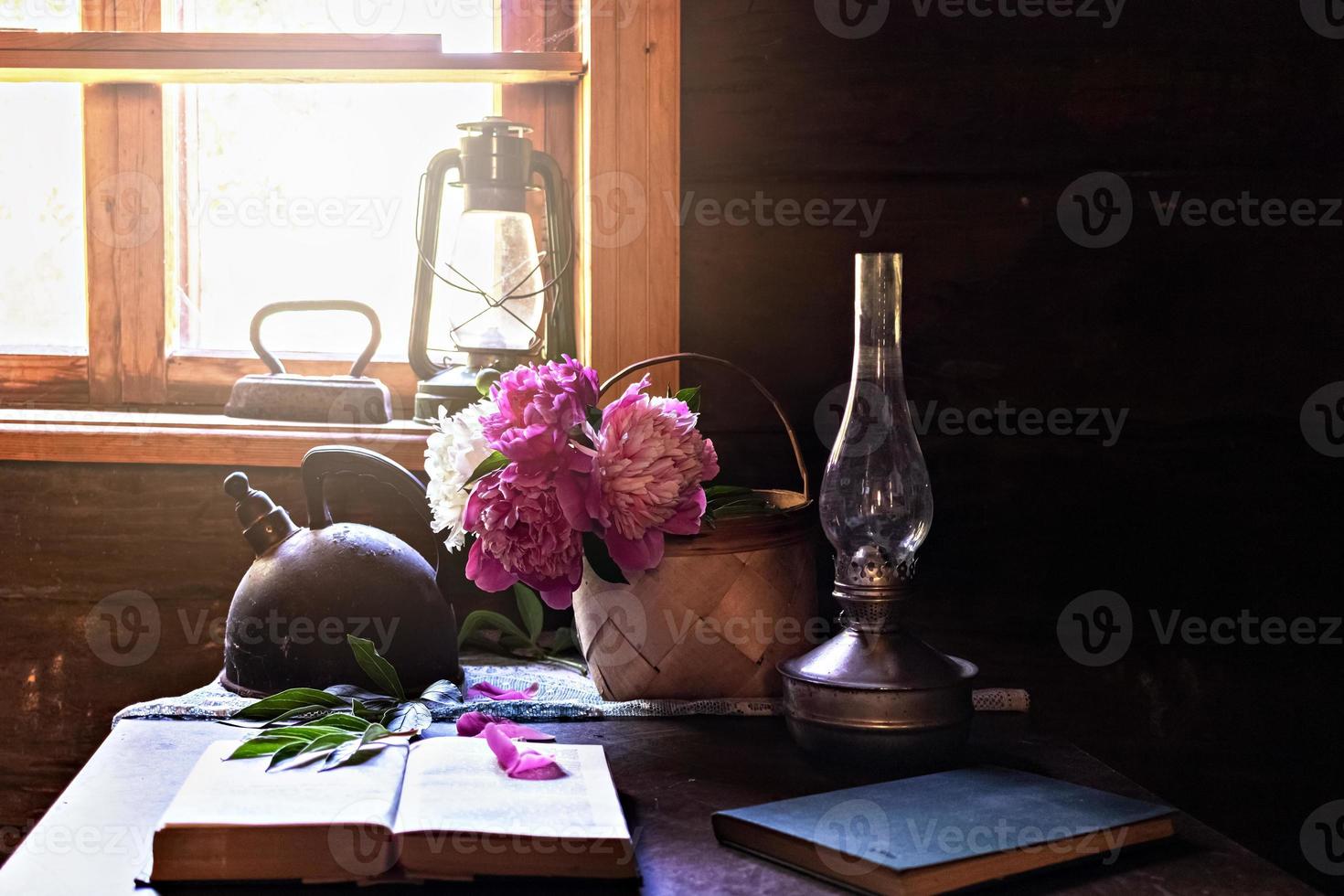 Still life of vintage items and a bouquet of peonies on a table by the window in an old village house. photo