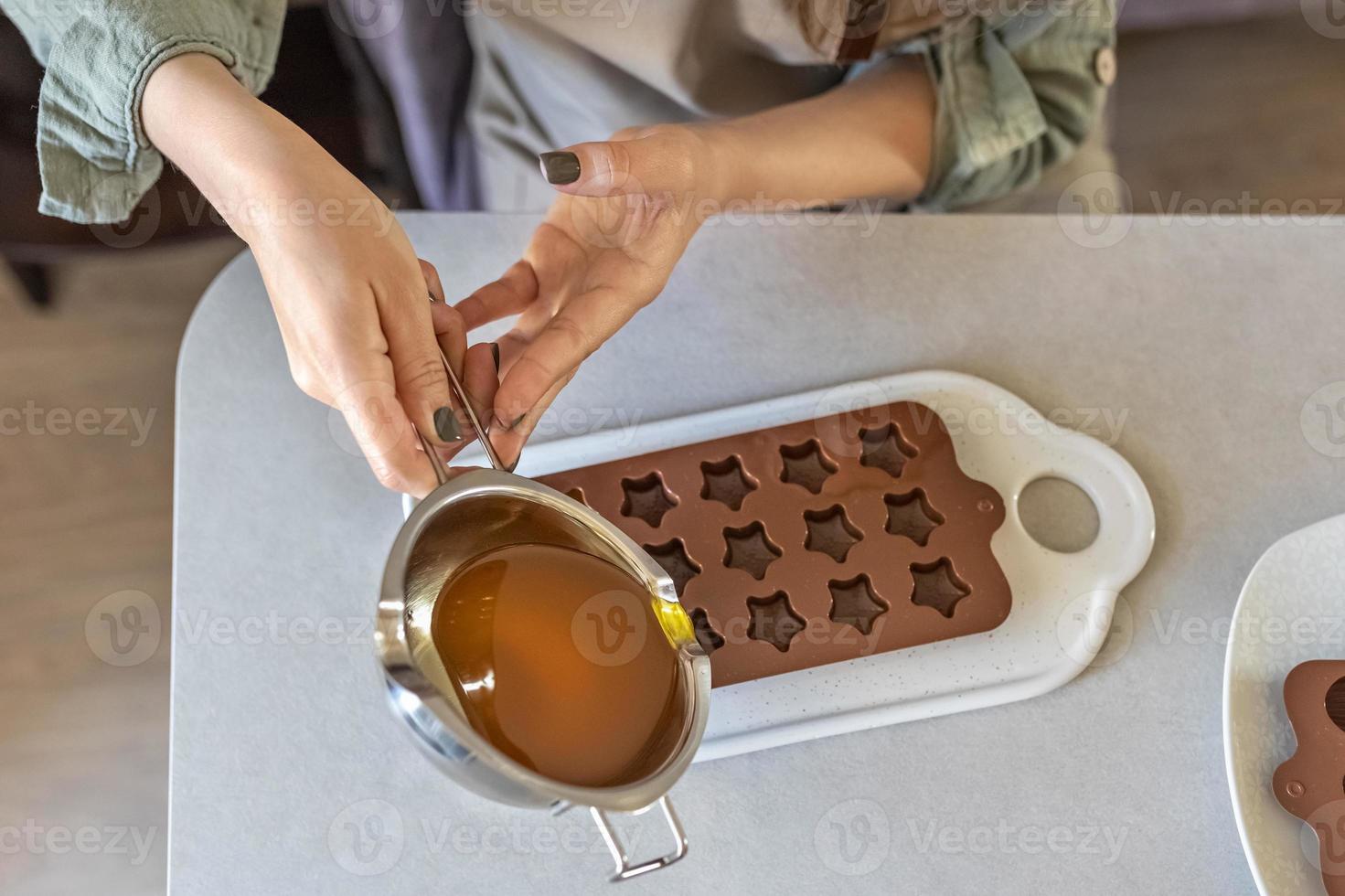 Soap maker a woman pours hot organic cocoa butter with aromatic oils into molds for making cosmetics for body skin care. photo