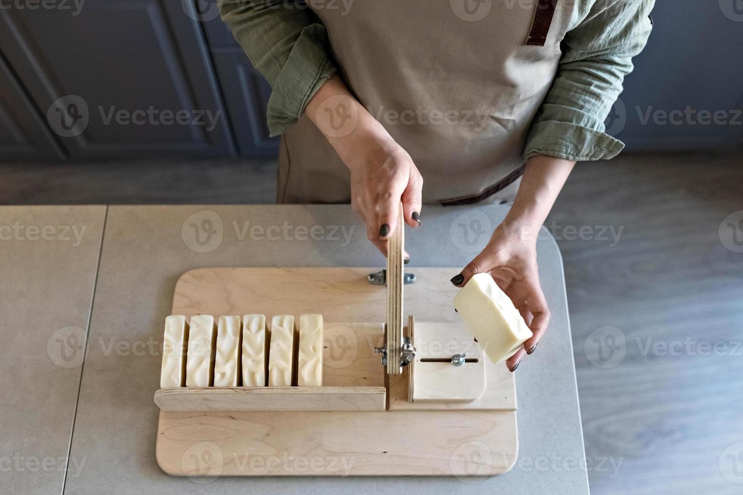 A woman makes handmade natural soap.The finished soap is cut into pieces using special machine. Home spa. Small business photo