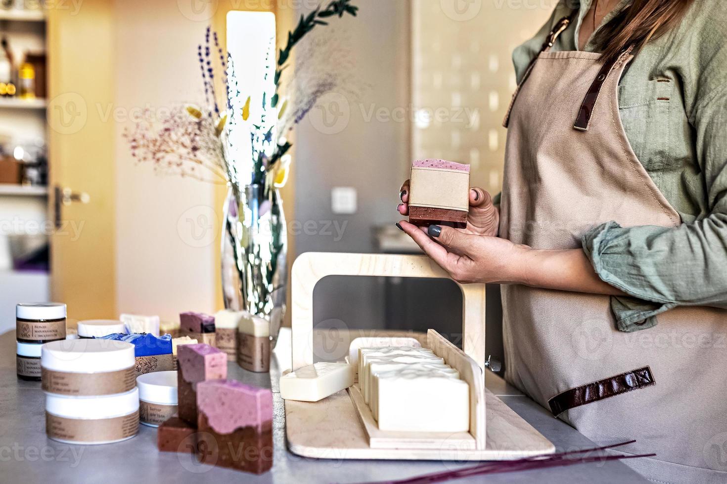 A soap-maker girl holds a piece of freshly brewed handmade soap in her hands.Cooking process.Home spa.Small business. photo