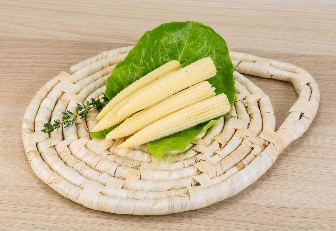 Baby corn on wooden board and wooden background photo