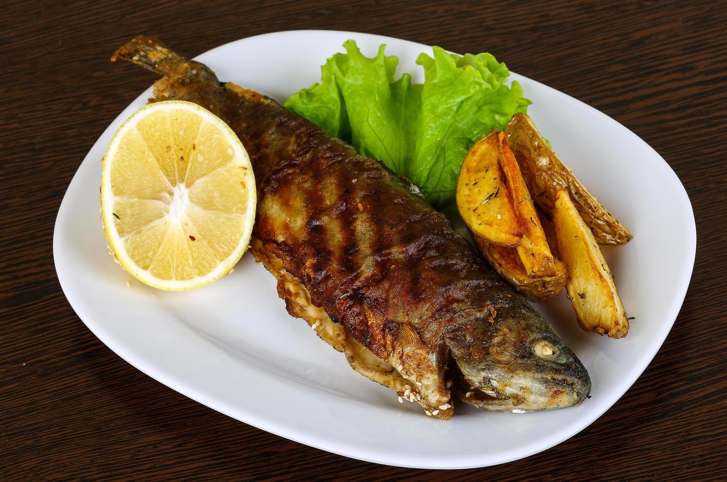Grilled trout on the plate and wooden background photo