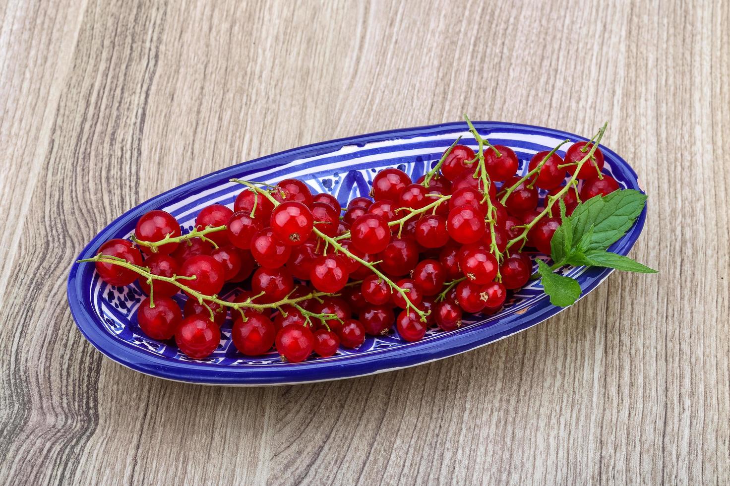 Red currants in a bowl on wooden background photo