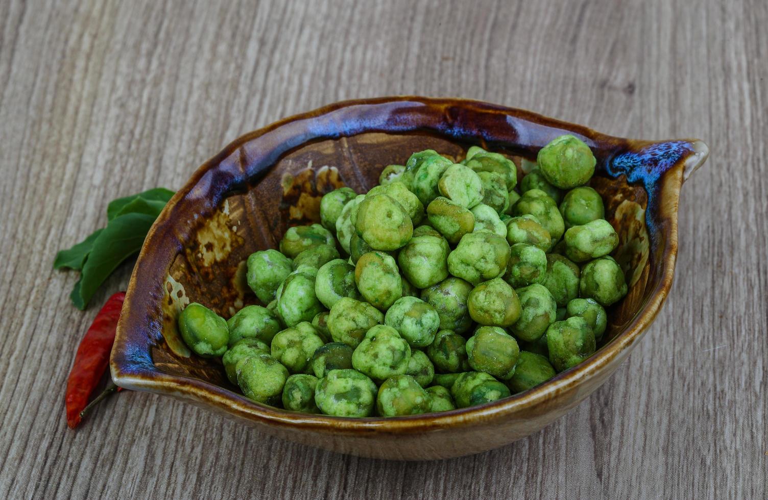 Wasabi peas in a bowl on wooden background photo