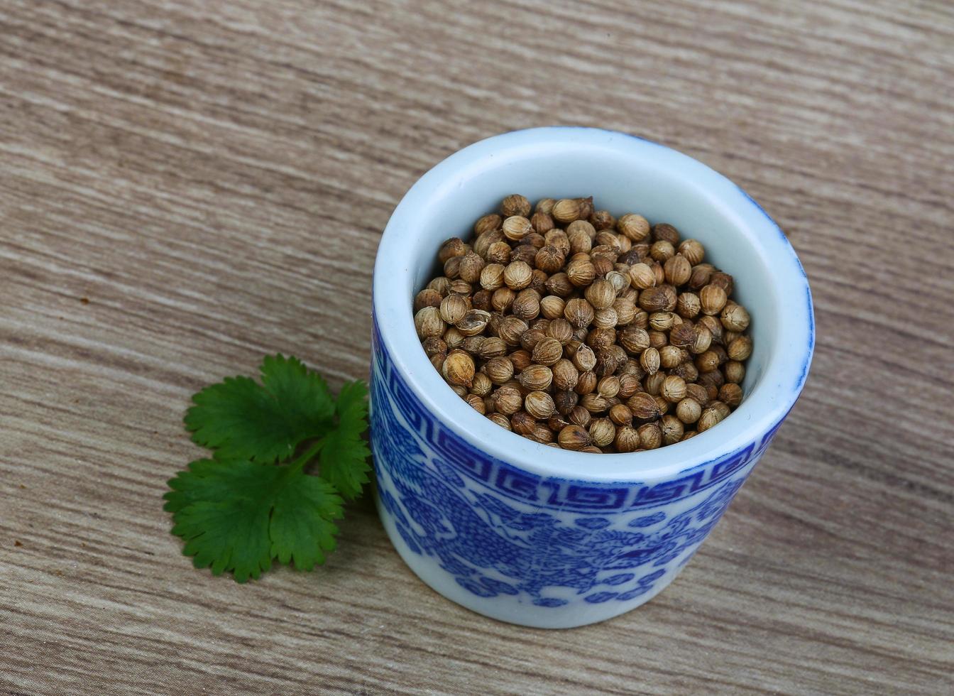 semillas de cilantro en un recipiente sobre fondo de madera foto