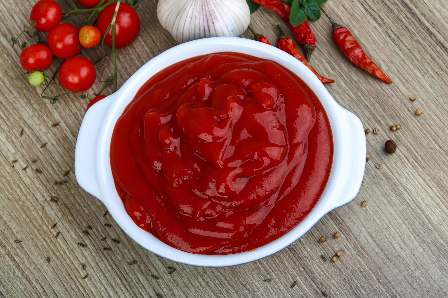 ketchup de tomate en un recipiente sobre fondo de madera foto