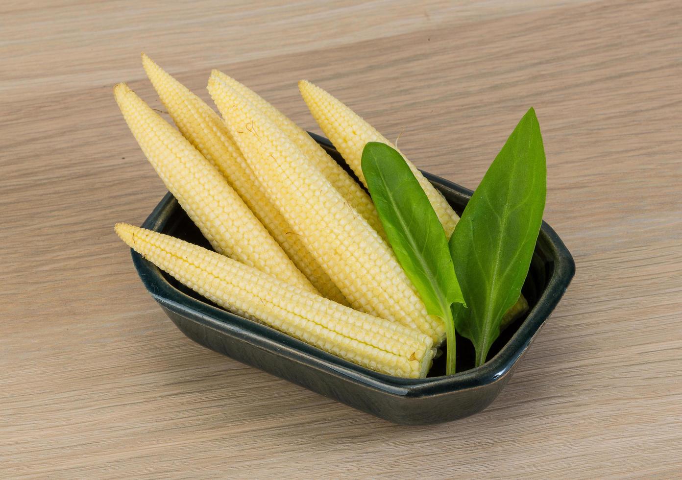 Baby corn in a bowl on wooden background photo