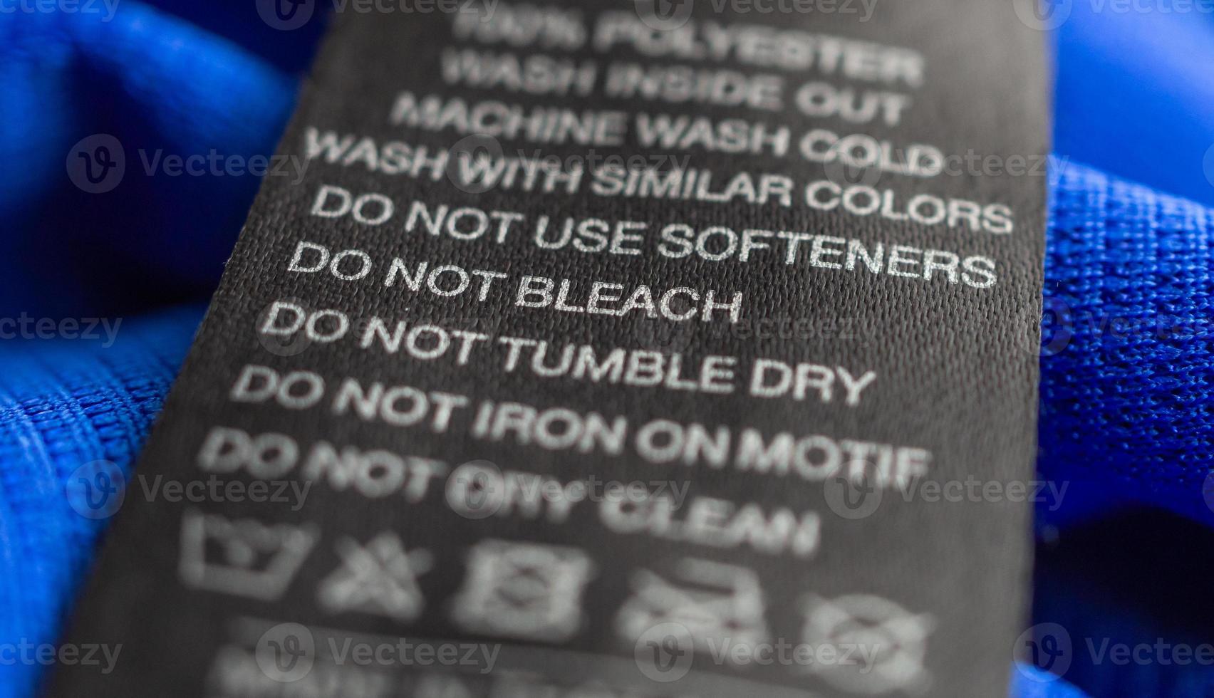 Black laundry care washing instructions clothes label on blue jersey polyester sport shirt photo