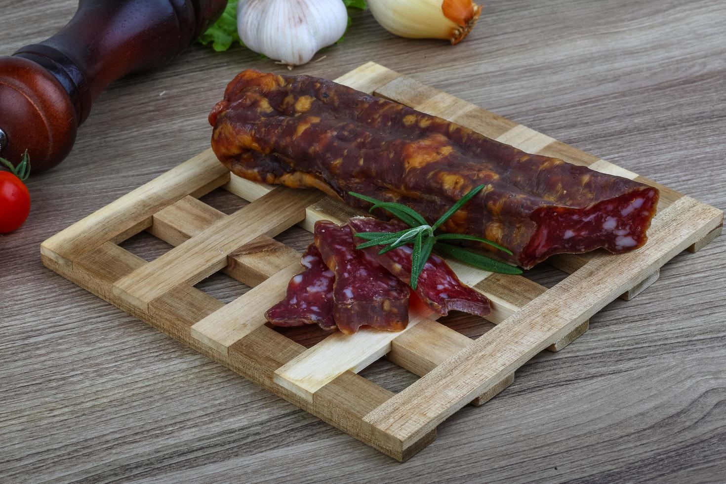 Salami sausage on wooden board and wooden background photo