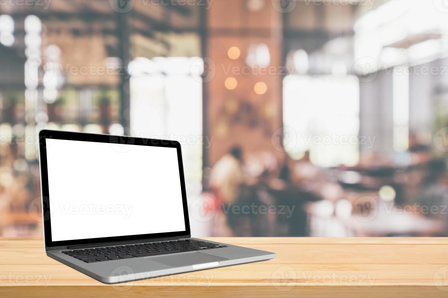 Blank white screen laptop computer on wood table top with cafe restaurant abstract bokeh light defocused blur background photo