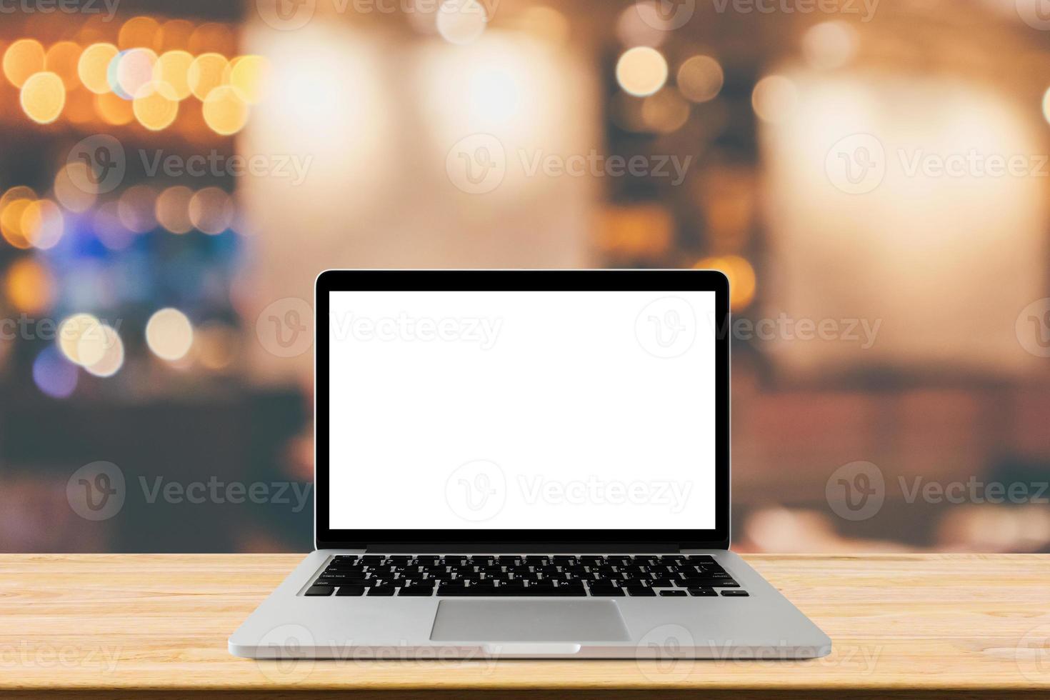 Blank screen laptop computer on wood table top with blur cafe restaurant with abstract bokeh light defocused background photo