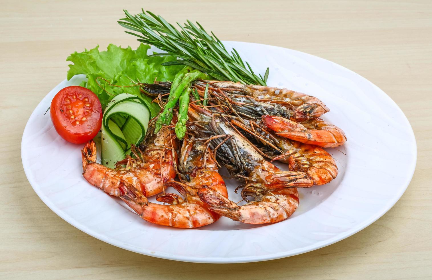 gambas a la parrilla en el plato y fondo de madera foto