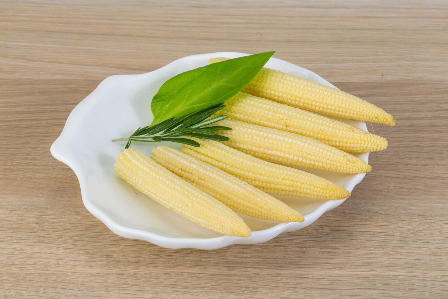 Baby corn on the plate and wooden background photo