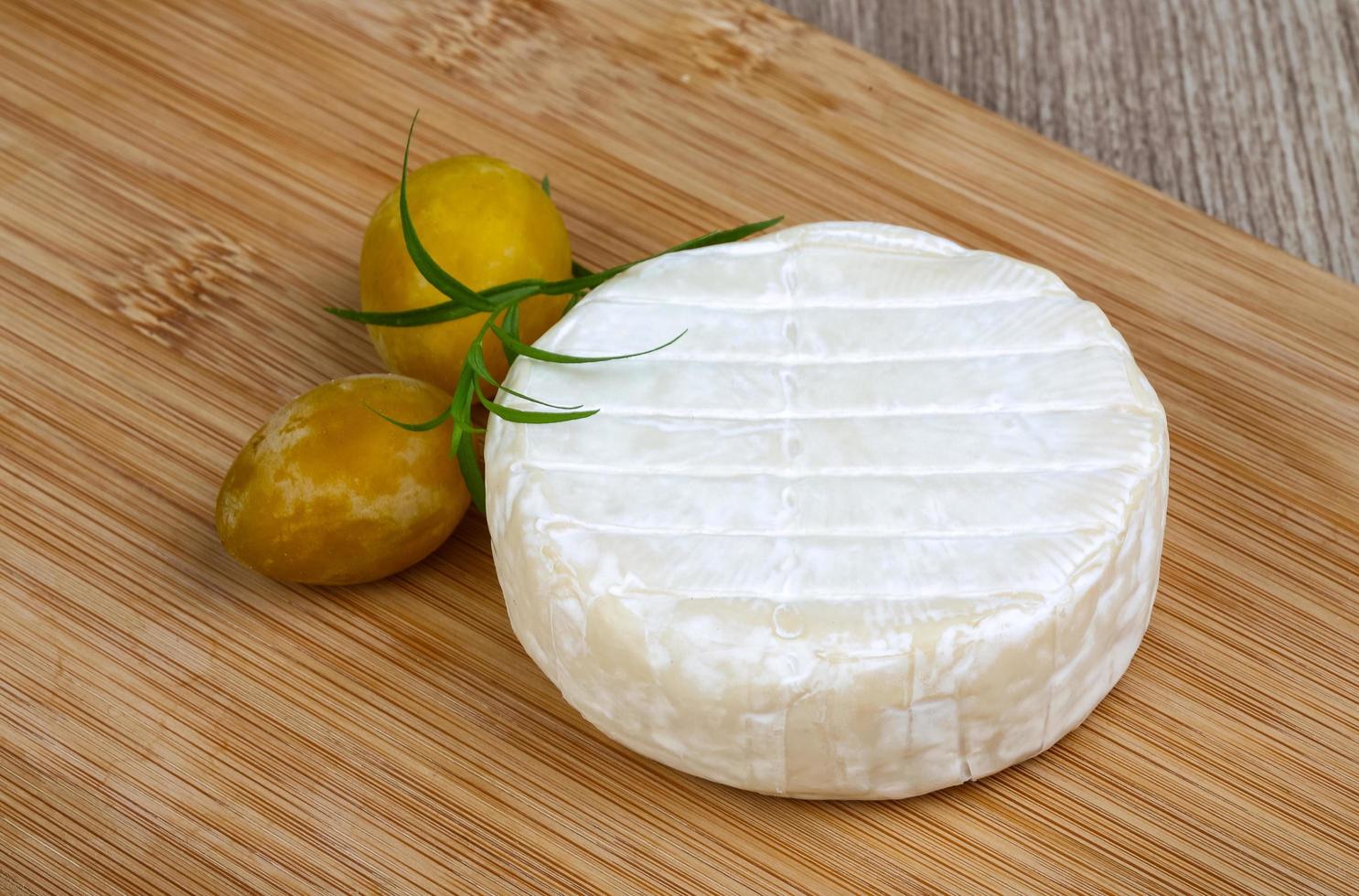 Brie cheese on wooden board and wooden background photo