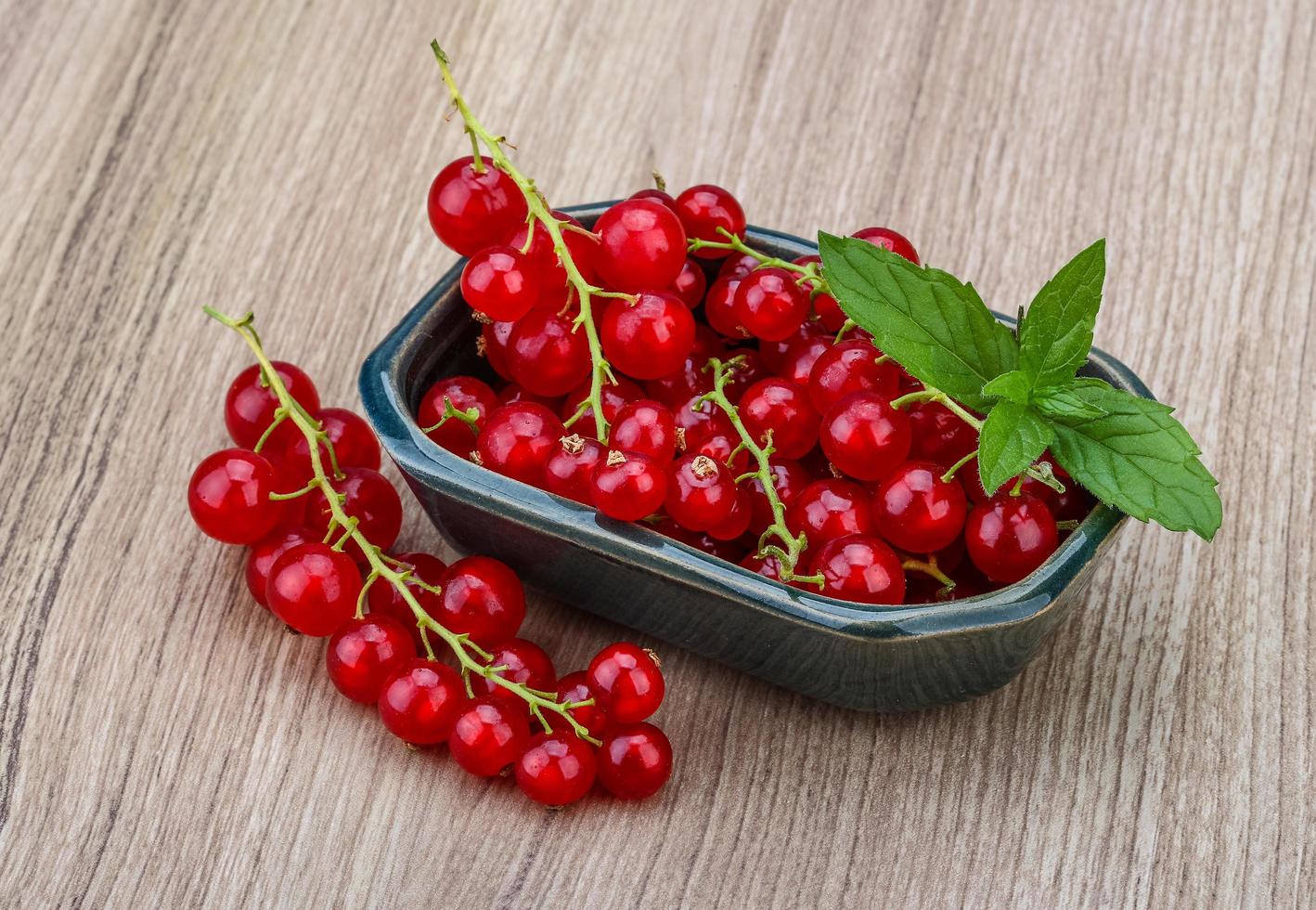 Red currants in a bowl on wooden background photo