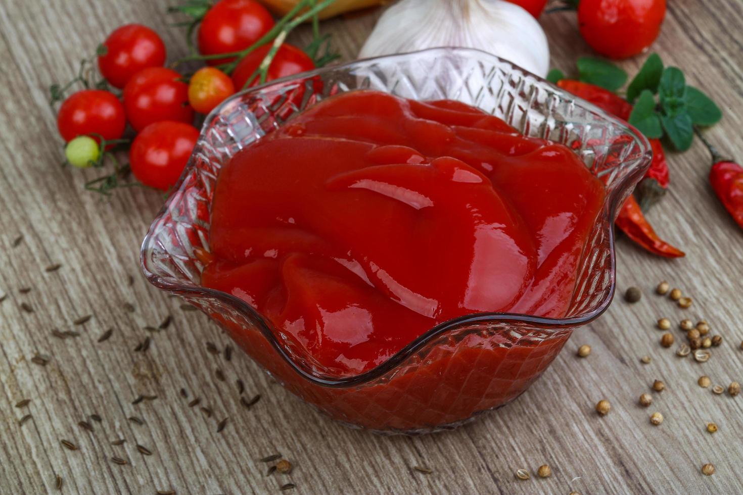 ketchup de tomate en un recipiente sobre fondo de madera foto