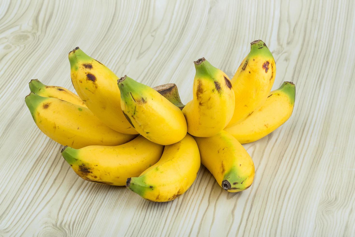 Baby banana on wooden background 12472887 Stock Photo at Vecteezy