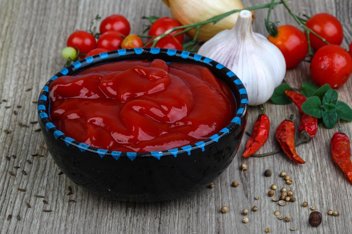 ketchup de tomate en un recipiente sobre fondo de madera foto