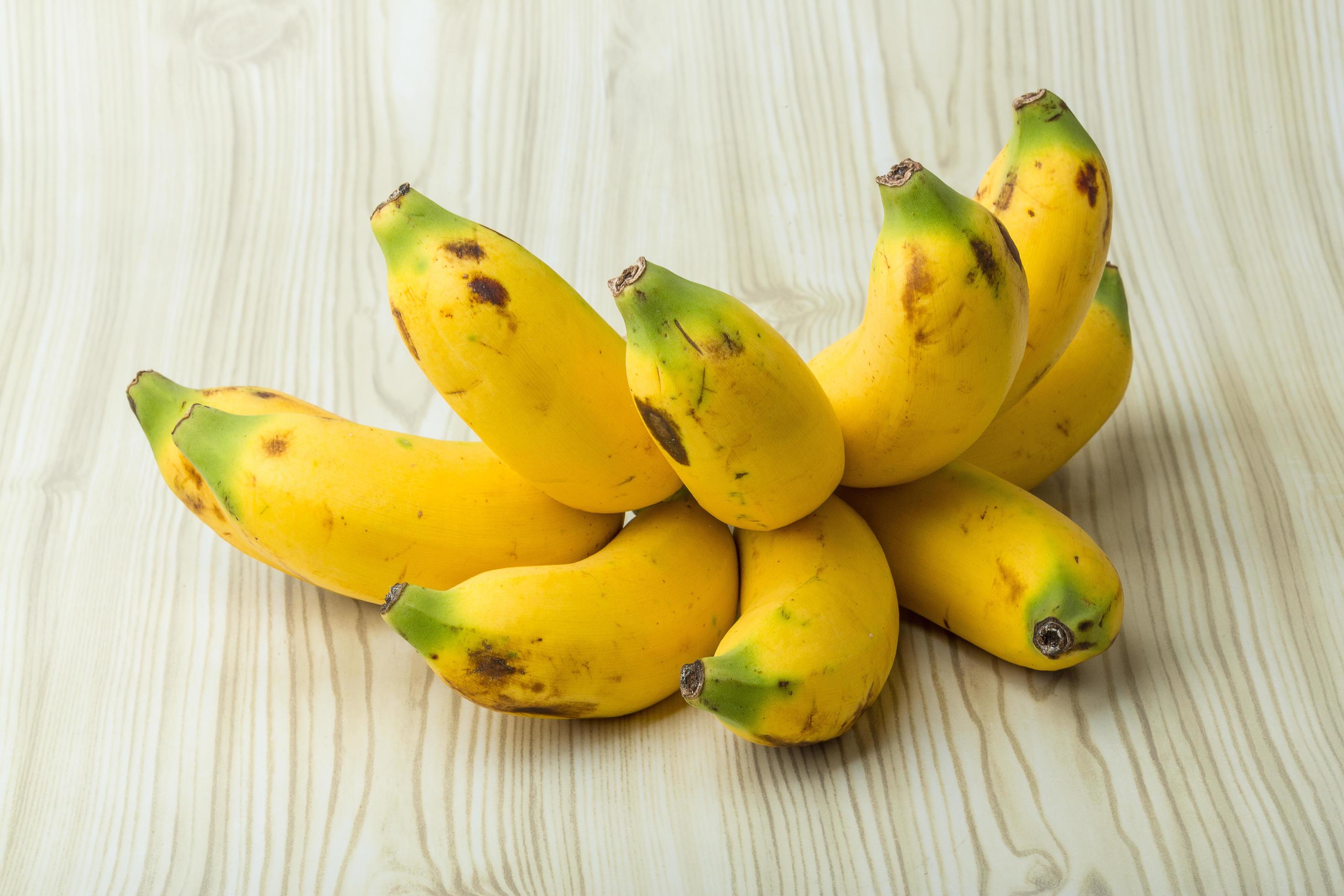 Baby banana on wooden background 12473222 Stock Photo at Vecteezy