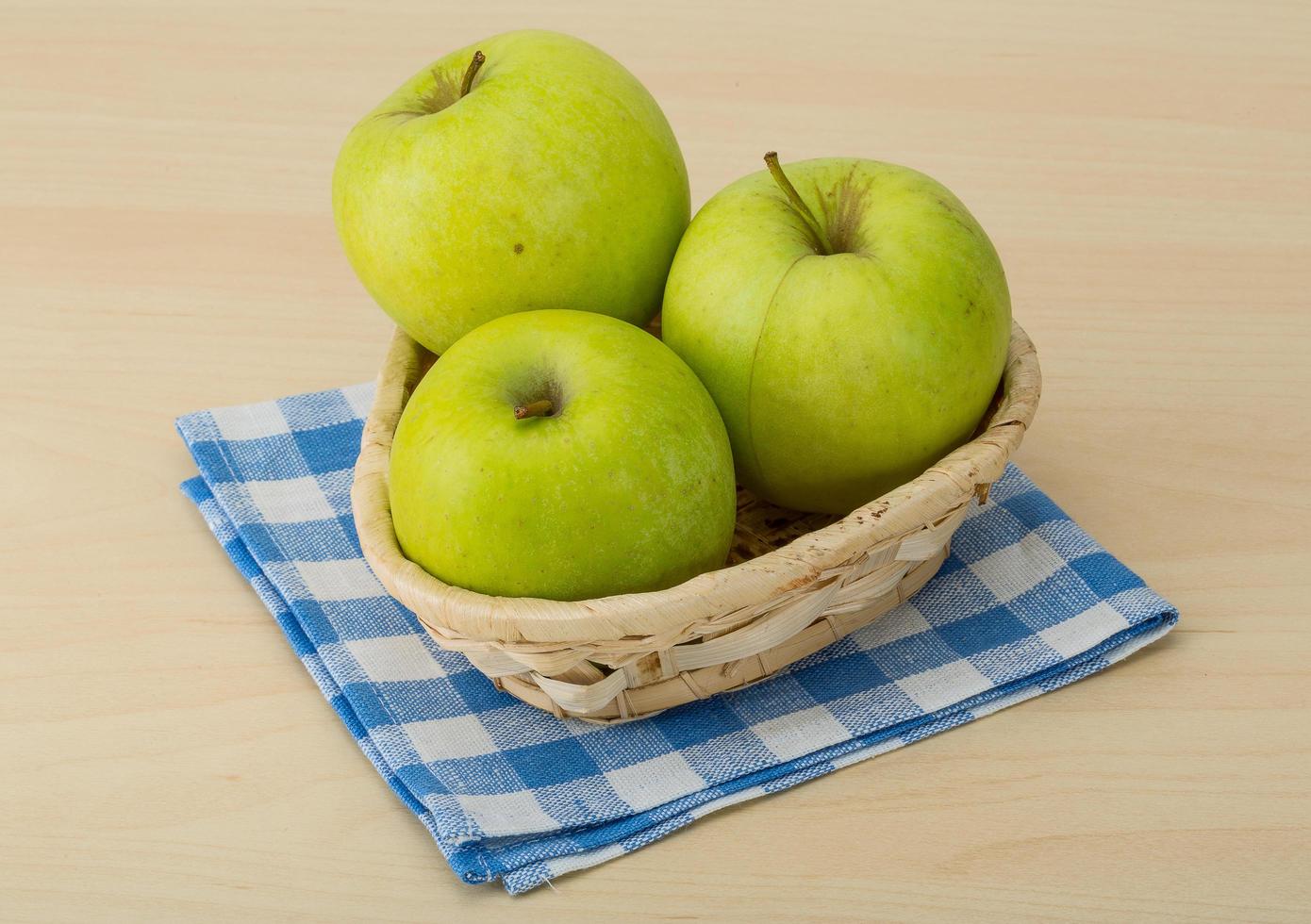 manzana verde en una cesta sobre fondo de madera foto