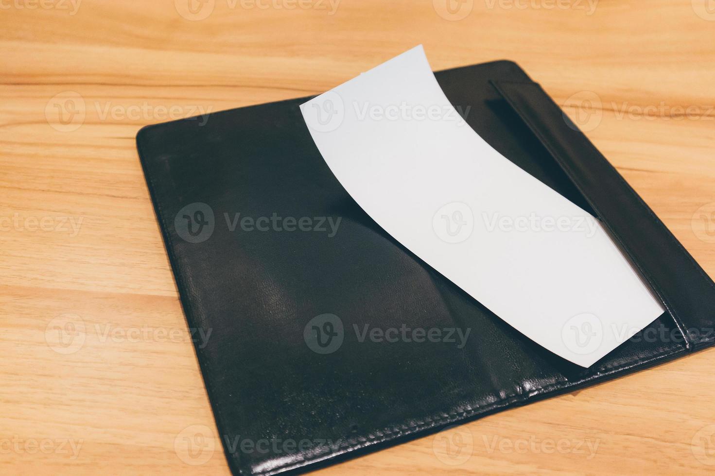 Blank empty white paper in restaurant payment billing receipt folder on wood table photo