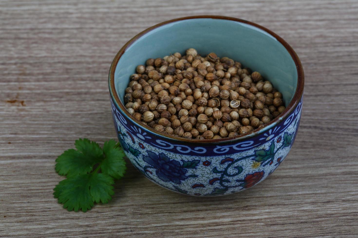 Coriander seeds in a bowl on wooden background photo