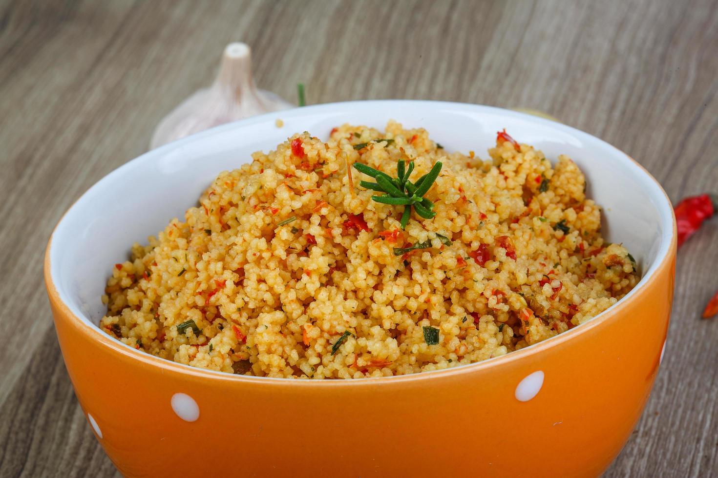 Couscous in a bowl on wooden background photo