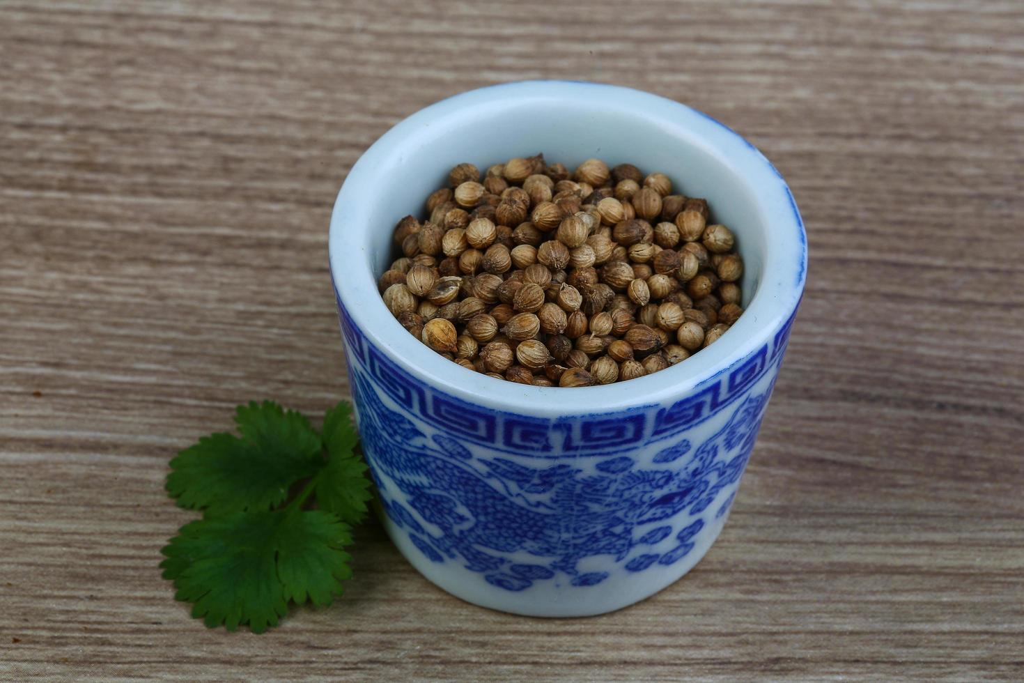 semillas de cilantro en un recipiente sobre fondo de madera foto